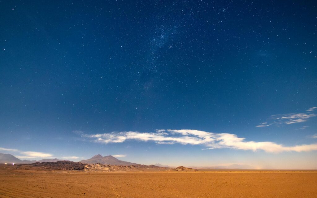 the night sky over a desert with a large star