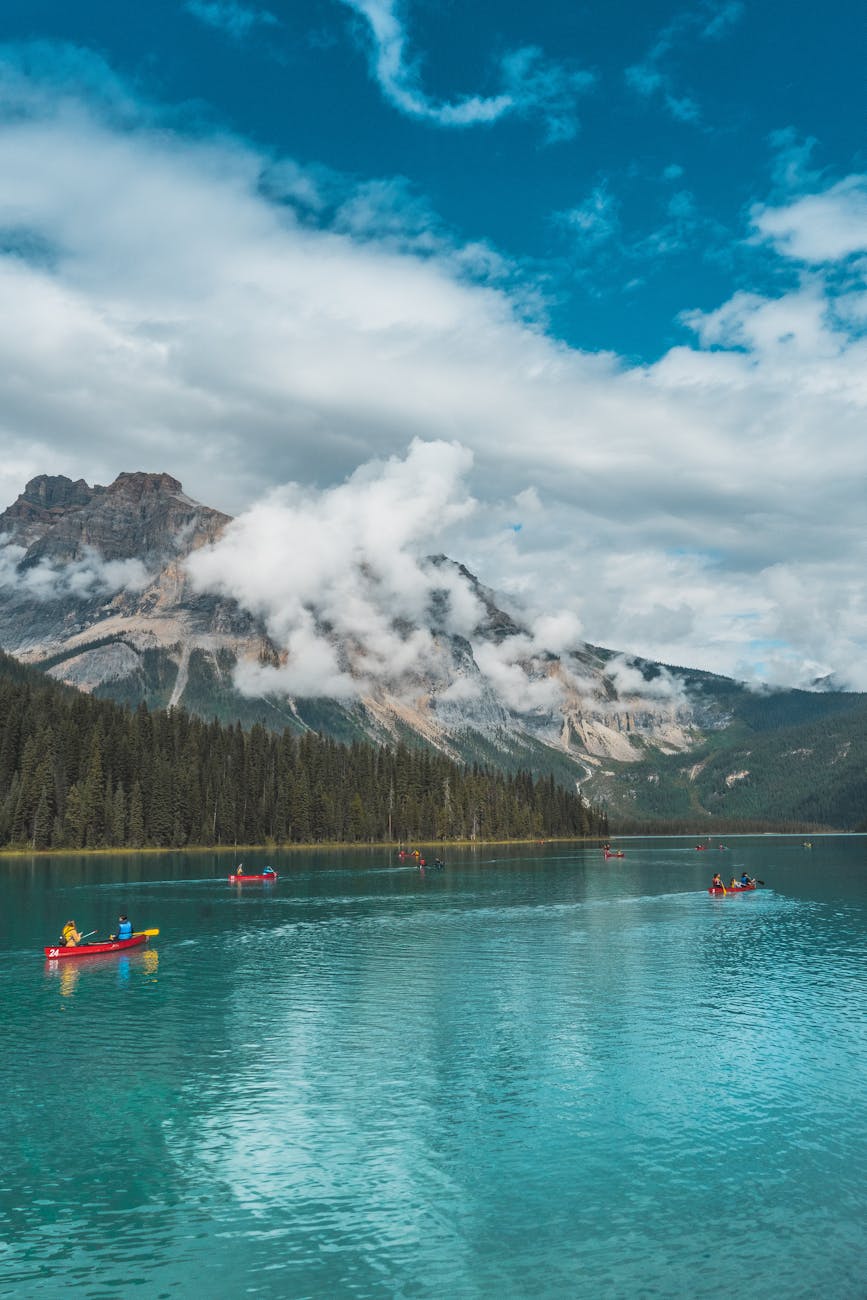 photo of people riding kayak on lake across mountain