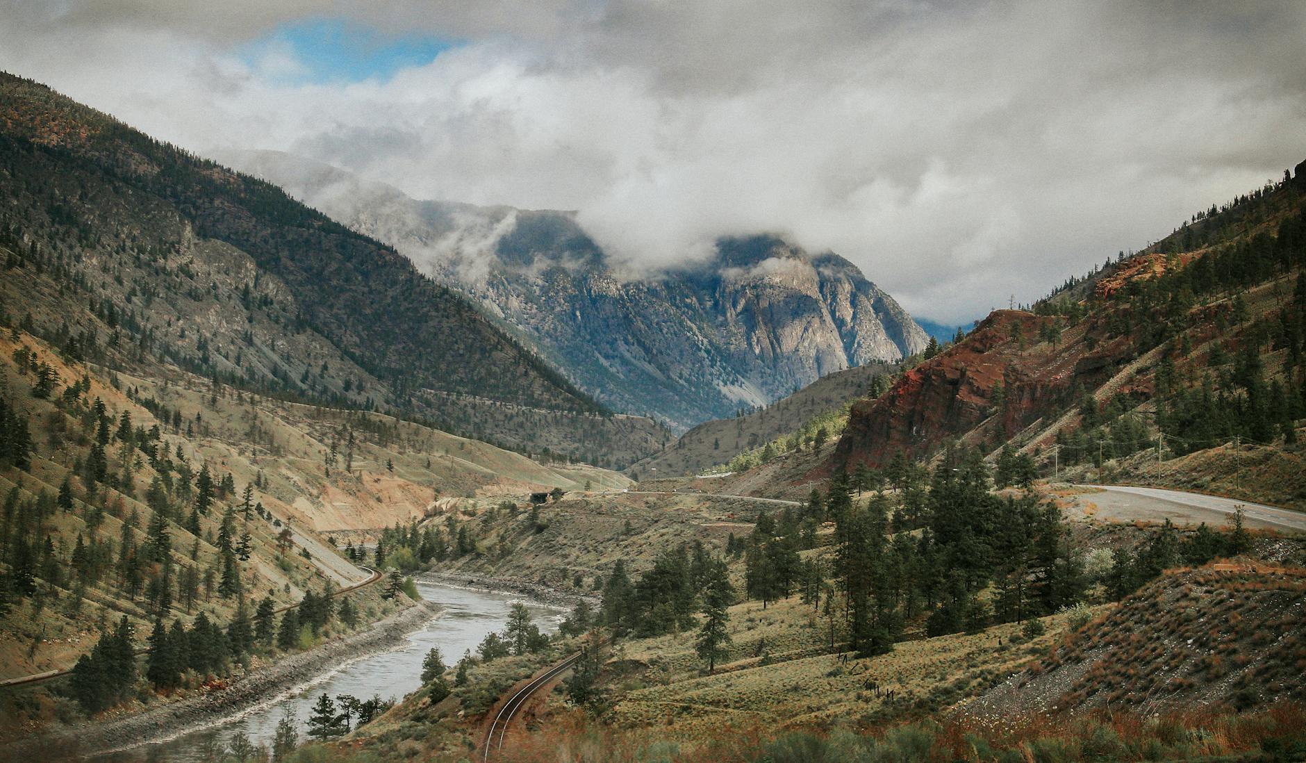 river between mountains under cloudy sky