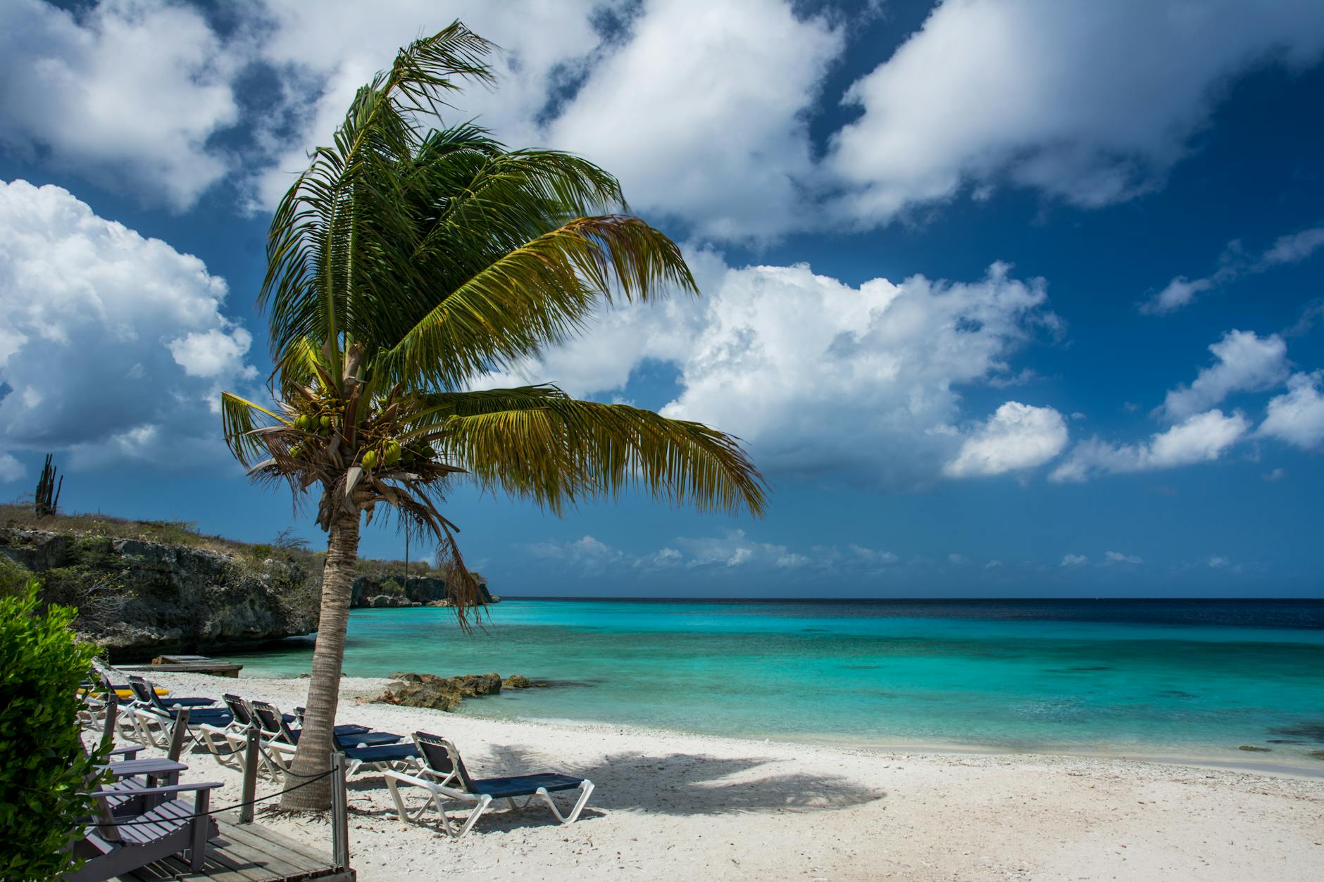 A secluded white-sand beach meets crystal-clear turquoise waters along Curaçao’s rugged coastline.