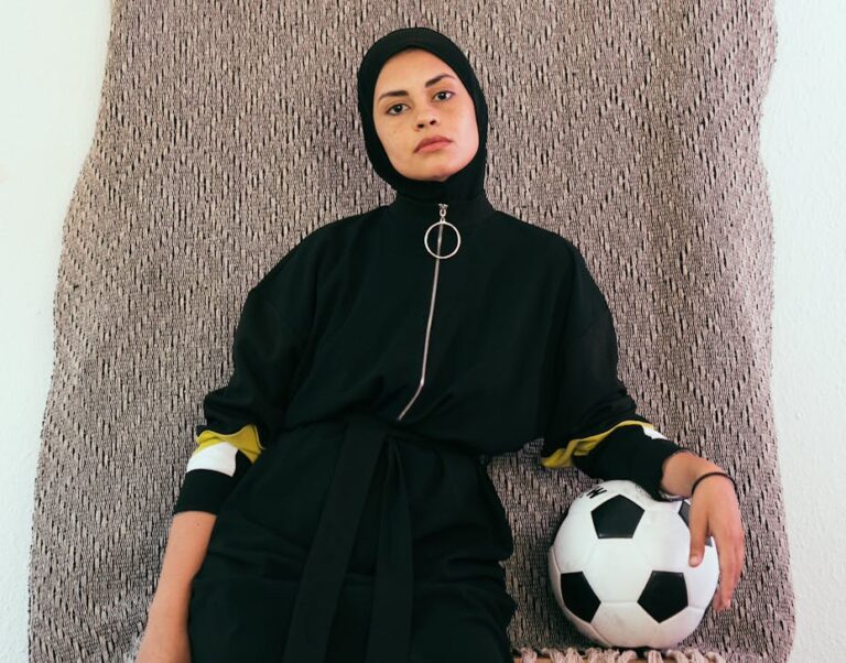 photo of woman in black hijab holding soccer ball