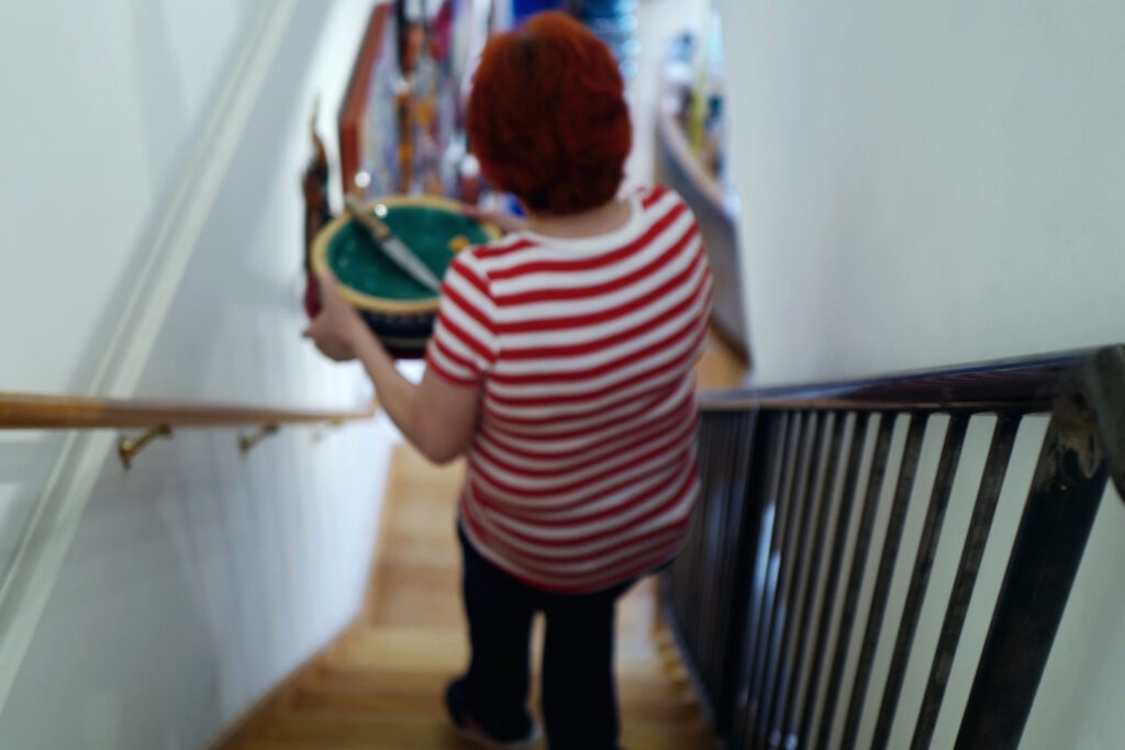 artist studio woman carry plate downstairs